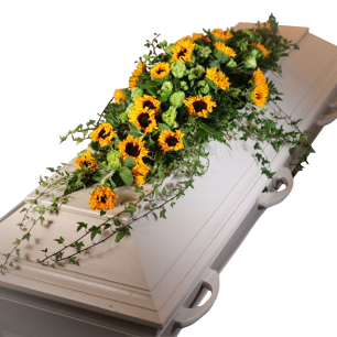 Vit kista dekorerad med en blomsterarrangemang av solrosor och gröna kvistar.