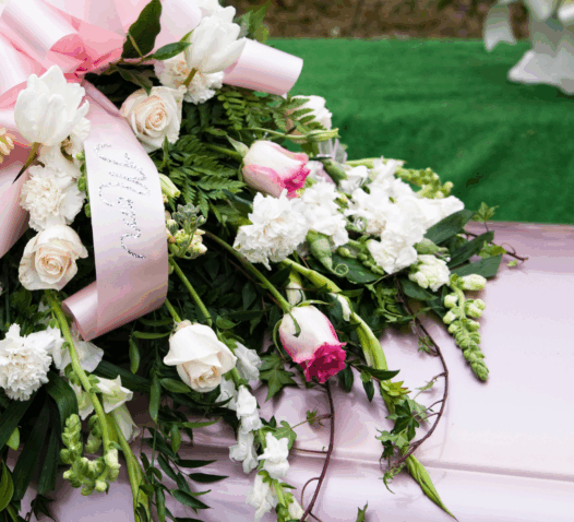 En kista dekorerad med en bukett vita och rosa blommor och en rosa rosett.